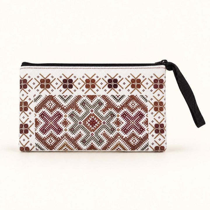 A small zippered pouch with a white background and an intricate geometric embroidered pattern in brown, burgundy, and olive green. It features a black zipper and a black wristlet strap on the right side, set against a plain off-white background.