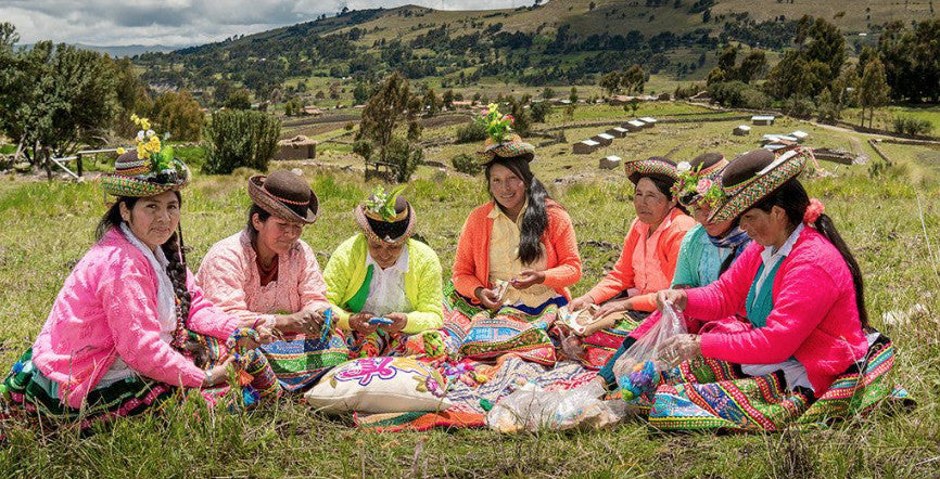 Group of women artisans in Peru creating traditional colorful textiles outdoors