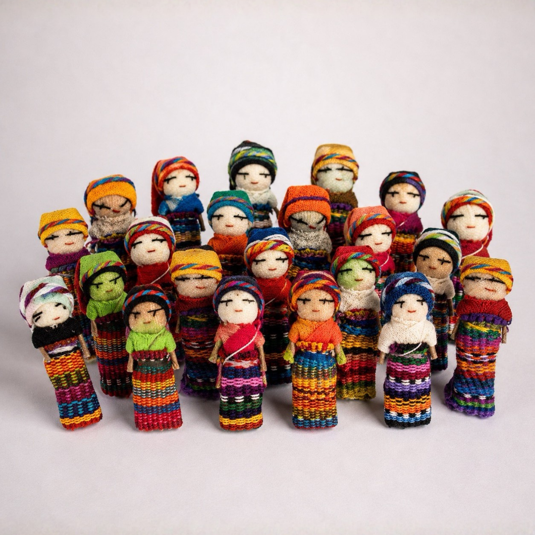 A group of colorful hand-knit Guatemalan worry doll figurines arranged in rows on a light gray studio background.